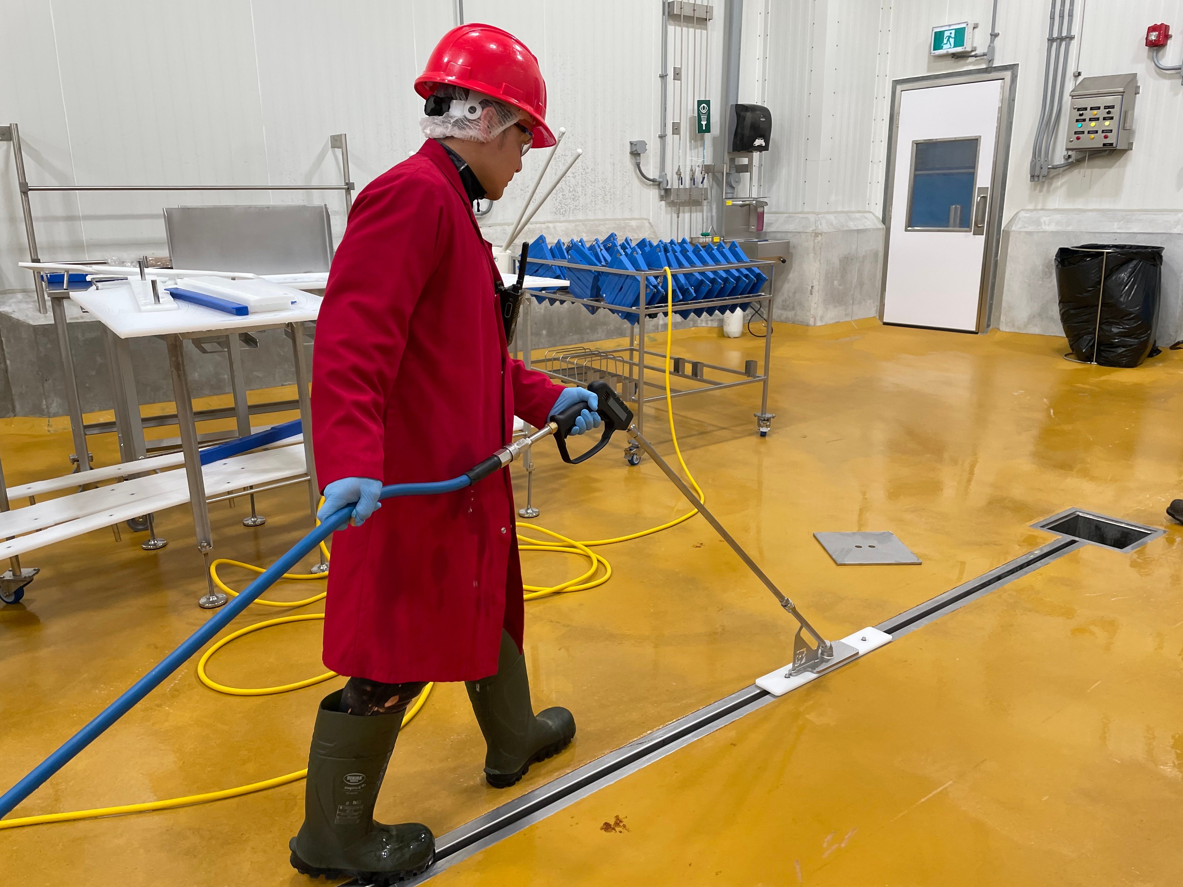 a worker using the slot dog to clean a slot drain